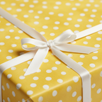 Playful yellow polka dot wrapping paper with a white satin ribbon and bow, perfect for a cheerful birthday or baby shower gift.