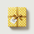 Yellow polka dot wrapping paper with a gold ribbon and "Wrapped Studios" gift tag, perfect for birthday or baby shower gifts.